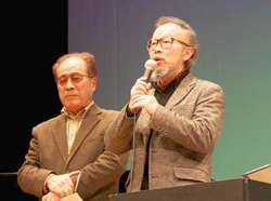 阿部先生（右）も自作のメロディーで町民憲章を熱唱。左は伊里前地区自治会長の熊谷健一さん